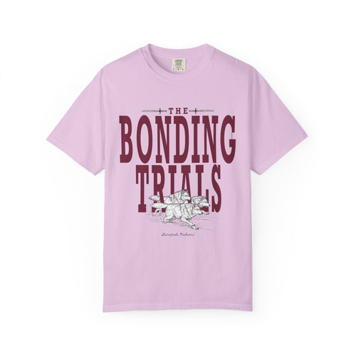 Comfort Colors lavender unisex graphic tee from thtgrlreads featuring a vintage wash and bold "The Bonding Trials" text with an illustrated wolf design, part of the Wolves of Ruin collection.